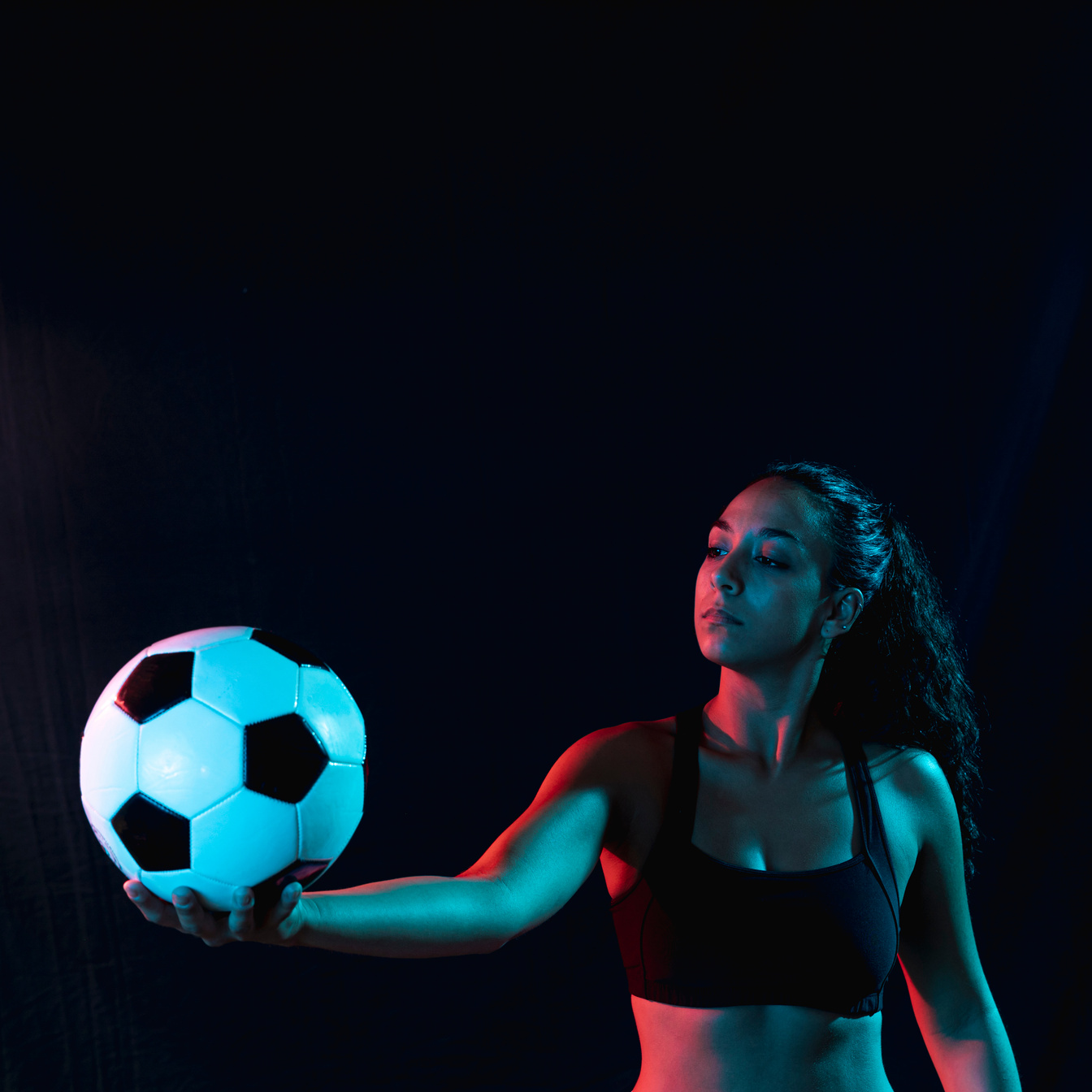 fit young woman holding soccer ball